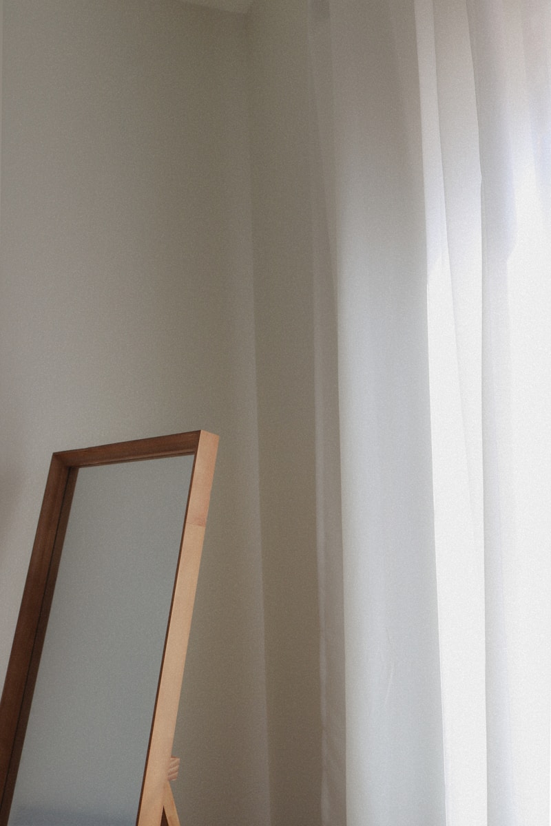 a mirror sitting next to a window in a room